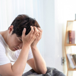 만성 피로와 두통으로 머리를 짚고 있는 남성