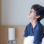 수면 부족으로 침대에 앉아 피로를 느끼는 남성